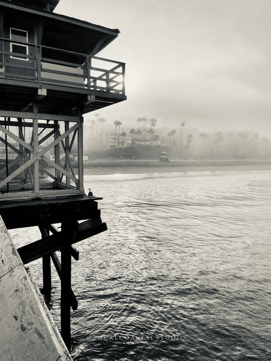 Black and white photo of a lifeguard tower fading into coastal fog.